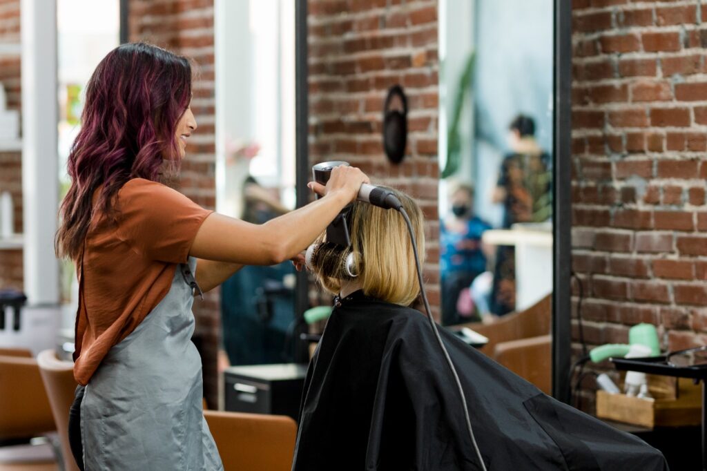 A woman receives a haircut from a hairdresser at a hair salon in Frisco